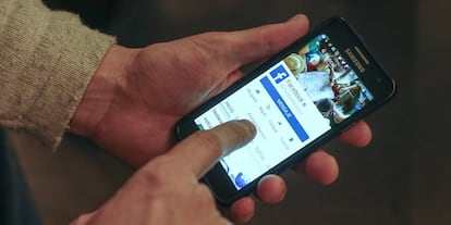 Un hombre consulta Facebook en el móvil.