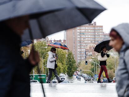 Varias personas se protegen de la lluvia en Madrid.