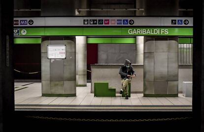 Una persona con mascarilla espera la llegada del metro en una estación de Milán.