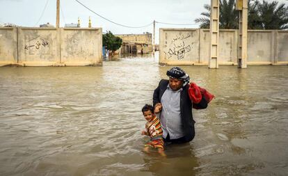 Un hombre lleva en brazos a su hijo por una calle inundada por las fuertes lluvias, este martes en Khorramabad (Irán). Los medios locales han informado de que al menos 45 personas han fallecido a causa de las lluvias torrenciales que se han sucedido durante las dos últimas semanas y que han afectado a 23 de las 31 provincias del país.