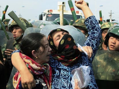 Mujeres de la minoría uigur rodeadas por policías chinos en Urumqi, durante los disturbios de julio de 2019.