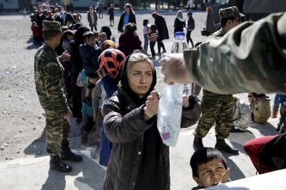 Una inmigrante recibe una porcin de comida y agua en un campamento en Schisto, cerca de Atenas (Grecia).