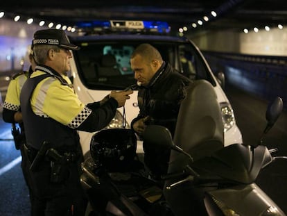 Un agente de la Guardia Urbana de Barcelona hace la prueba de alcoholemia a un motorista. 