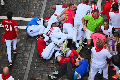 Corredores caen al suelo durante el séptimo encierro de los Sanfermines. 