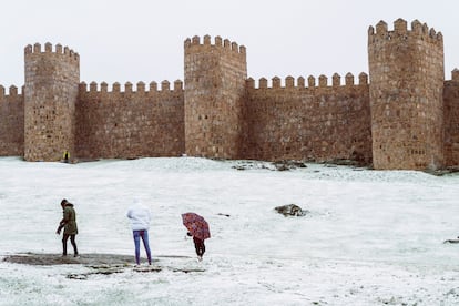 Tres personas caminan bajo la nieve en Ávila.