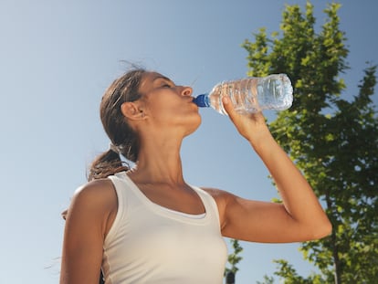 Una mujer bebe de una botella de agua de plástico.