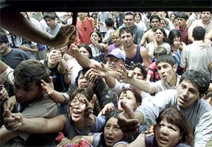 Decenas de personas piden comida frente a la puerta de un supermercado de Buenos Aires.
