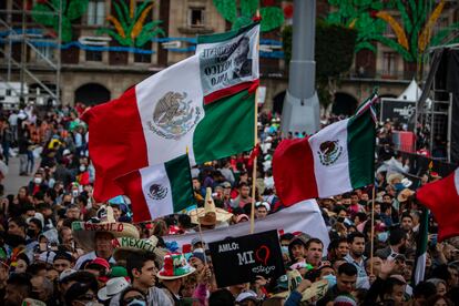 Tres banderas ondean por encima de la gente reunida.