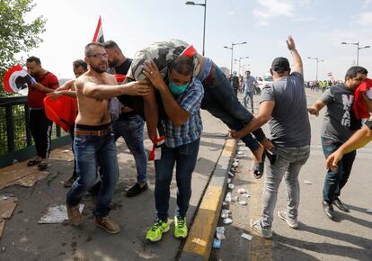 Varios manifestantes llevan a un hombre que se desmayó por el efecto del gas lacrimógeno durante una protesta en Bagdad.