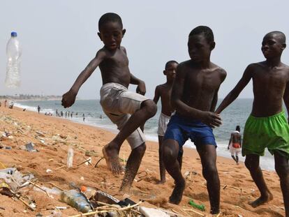Un grupo de niños juega con una botella de plástico en una playa de Costa de Marfil.
