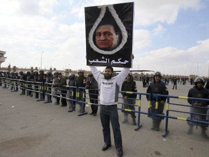 Un detractor del expresidente egipcio Hosni Mubarak, sostiene una pancarta donde se puede leer &#039;veredicto del pueblo&#039;, frente a la Academia Policial donde hoy, se ha reanudado el juicio en El Cairo (Egipto)