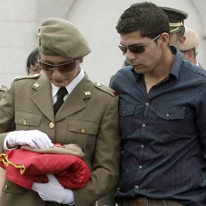 La hermana de la soldado Pineda, acompañada por su esposo, sostiene la bandera que cubría el féretro.