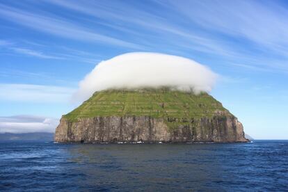 Litla Dimun, pequeña isla rocosa con un sombrero de nubes en un día soleado.