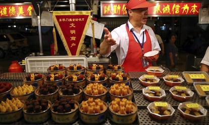 Un vendedor coloca envases con fruta en el antiguo mercado nocturno de Donghuamen