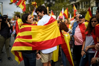 Una pareja participa en la manifestación con una bandera de España y Cataluña.