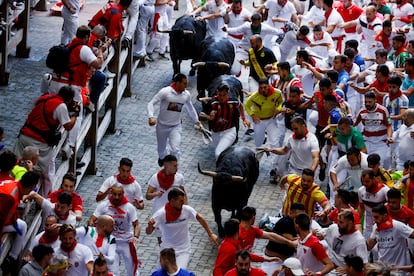 Corredores junto a los astados de Jandilla a su llegada a la plaza de toros de Pamplona, este viernes.