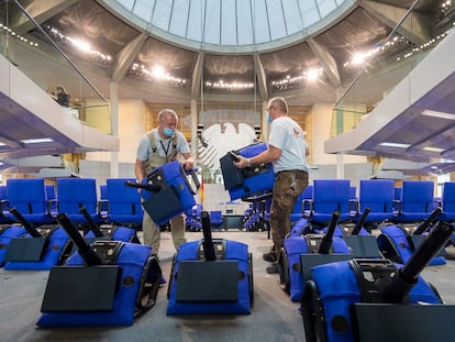 Dos operarios instalan nuevas hileras de asientos en el hemiciclo del Bundestag el 15 de octubre de 2021, antes de la sesión inaugural de la legislatura.