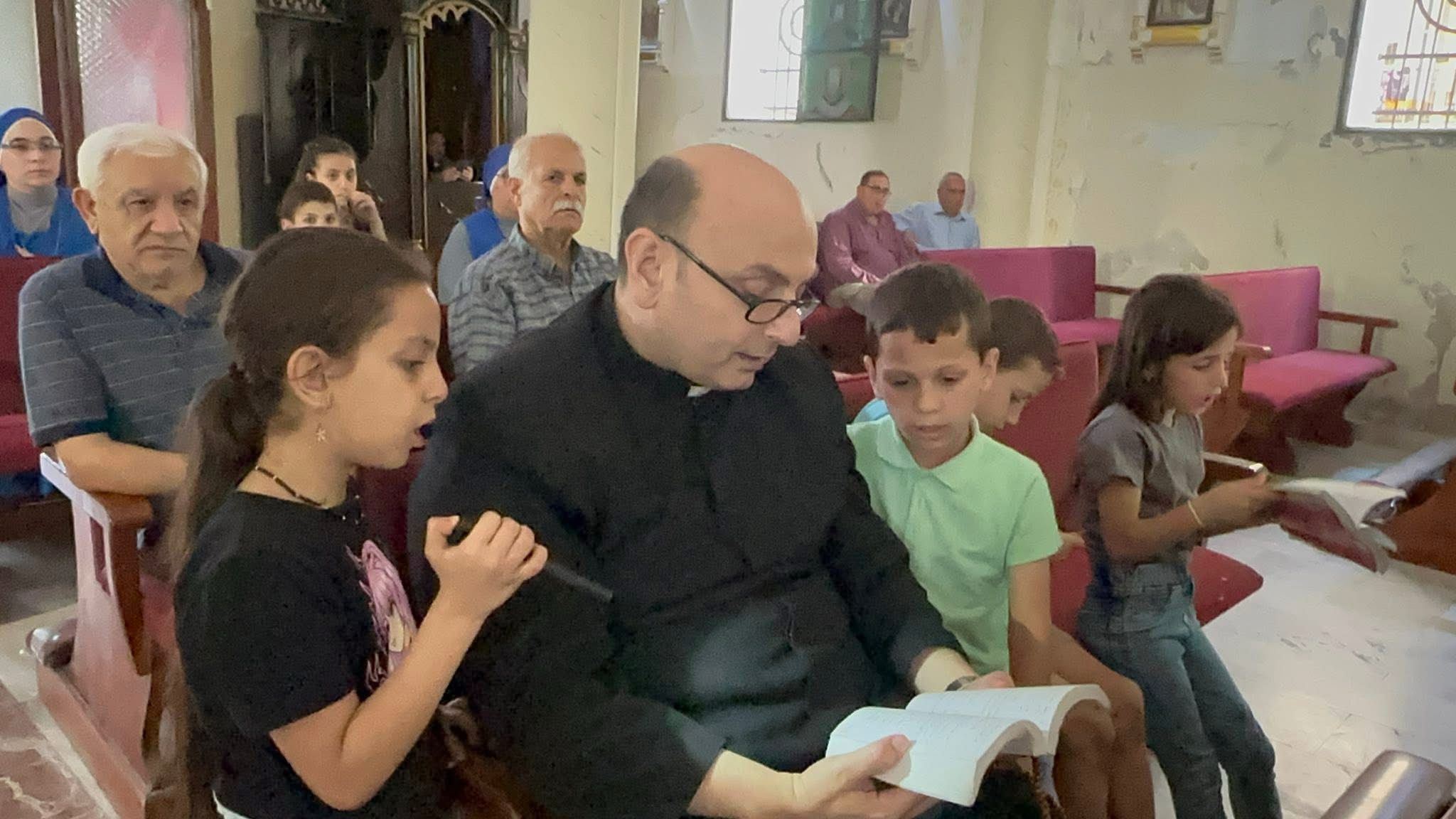 El sacerdote argentino Gabriel Romanelli, junto a dos niños, en la iglesia de Gaza en mayo.
