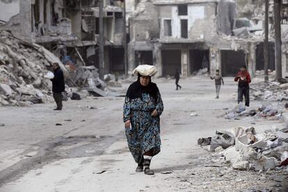 Una mujer camina a través de los edificios dañados del barrio de al-Shaar, en Alepo (Siria).