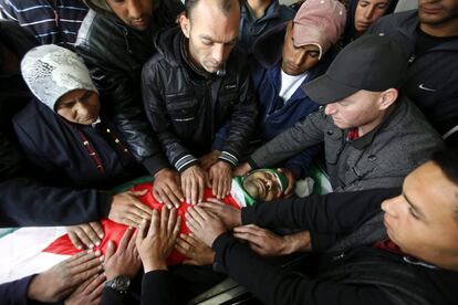 Familiares acarician el cuerpo del joven palestino Qasim Jaber durante su funeral en la ciudad cisjordana de Hebrón. Tres palestinos murieron ayer en dos ataques diferentes a la entrada de una colonia judía al sur del territorio ocupado de Cisjordania, donde cuatro militares israelíes resultaron heridos a causa de los disparos de dos palestinos contra las personas que esperaban en una parada de autobús.