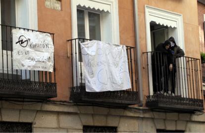 Varios <i>okupas</i> se asuman a las ventanas del bloque "liberado" en la calle Concepción Jerónima de Madrid.