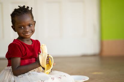 A medida que la covid-19 sigue dificultando la prestación de los servicios esenciales y aumenta el número de familias en situación de pobreza, la pandemia influye aún más en la forma en que los padres alimentan a sus hijos. Emerald Atyang, ugandeda de tres años y 10 meses, degusta un plátano después de disfrutar de una comida nutritiva en el almuerzo. Esta consistió en arroz, calabaza, guisantes, verduras rojas y aguacate. El plátano es su fruta favorita.