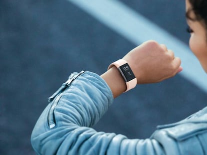 Una usuaria de una pulsera de actividad mira la hora en su Fitbit Charge 2.