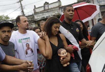 Vanessa Francisco Sales leva uma boneca que foi de sua filha, Ágatha Félix, de mãos dadas com Adegilson Félix, seu marido e pai da menina que morreu vítima de um tiro, durante o cortejo do corpo da criança.