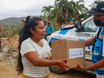 Un voluntario de la Fundación Carlos Slim entrega una caja con ayuda humanitaria a una mujer en Acapulco.