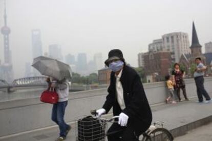 La contaminación de Shanghai obliga a una ciclista a usar mascarilla.
