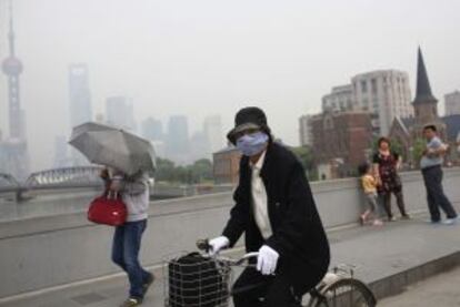 La contaminaci&oacute;n de Shanghai obliga a una ciclista a usar mascarilla.