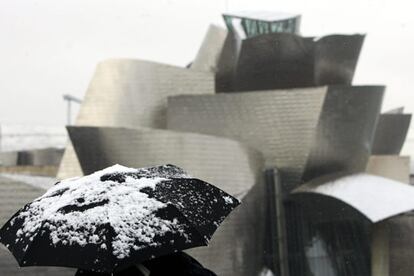 Una persona contempla, con su paraguas cubierto de nieve, el Guggenheim de Bilbao tras la nevada caída esta mañana en la capital vizcaína.