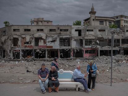 Several people wait at a bus stop in front of a building destroyed by the earthquake in Turkey, in the Turkish city of Kahramanmaras, on May 28, 2023.
