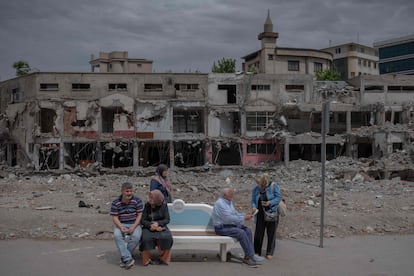 Several people wait at a bus stop in front of a building destroyed by the earthquake in Turkey, in the Turkish city of Kahramanmaras, on May 28, 2023.