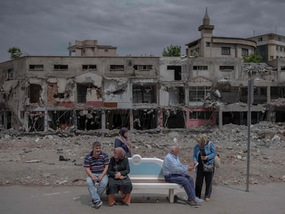 Varias personas esperaban el domingo en una parada de autobús frente a un edificio destruido por el terremoto en Turquía, en la ciudad turca de Kahramanmaras.