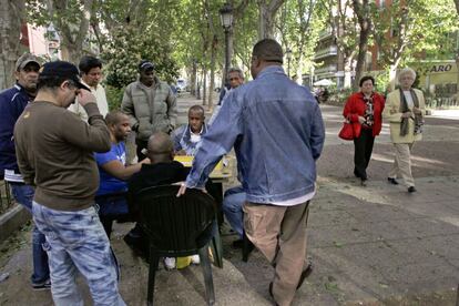 Un grupo de dominicanos juega al domino en el bulevar, en la calle de Peña Gorbea, en el distrito de Puente de Vallecas.