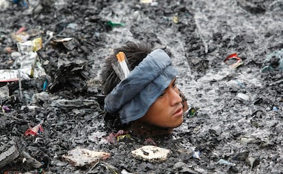 Un hombre camina entre el agua llena de escombros y escoria a la busqueda de objetos de valor tras un incendio que ha arrasado unas 500 casas a lo largo de un poblado costero en la ciudad de Malabon, al norte de Manila. El fuego, que se cree fue causado por una explosión de gas, comenzó antes del amanecer. No se ha informado de posibles víctimas, pero por lo menos 3.000 residentes perdieron sus hogares.