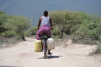 Sipha, una joven de 21 años, pedalea por los caminos de Msitu Wa Tembo cargada con varias garrafas de agua.