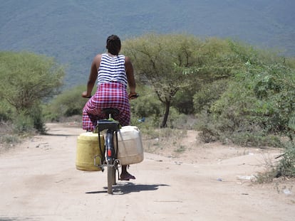 Sipha, una joven de 21 años, pedalea por los caminos de Msitu Wa Tembo cargada con varias garrafas de agua.