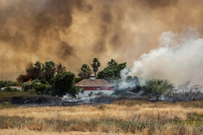 Los bomberos combaten las llamas cerca de una casa amenazada por un incendio en el área de Ludo, Faro, Algarve, sur de Portugal.