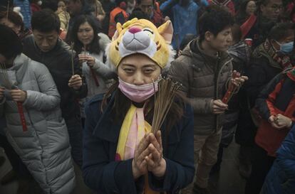 Una mujer ora con incienso de la buena suerte entre sus manos en el templo Yonghegong de Pekín (China).