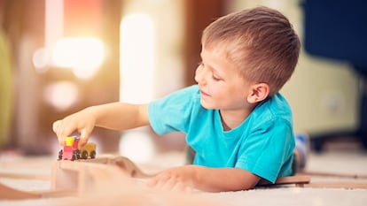 Un niño pequeño jugando con un tren de madera.