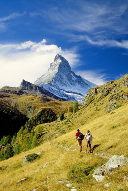 Senderismo en Suiza, con el fondo del espectacular pico Cervino (o Matterhorn) en forma de colmillo.