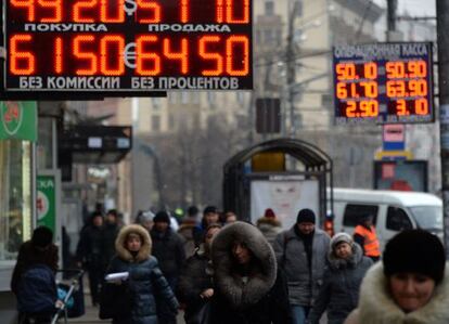 Peatones pasan bajo el letrero luminoso de una oficina de cambio en Moscú.