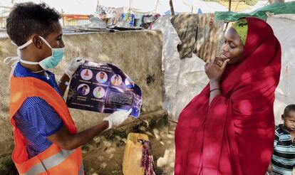 Una mujer residente en el campo de desplazados internos de Weydow, cerca de Mogadiscio (Somalia)  es informada por un trabajador humanitario sobre cómo protegerse para evitar contagiarse de covid-19 el 10 de junio de 2020.