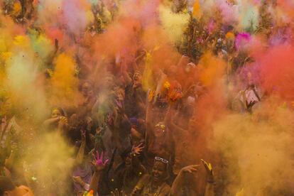 Los asistentes a la fiesta esparcen polvos de colores en el aire que se mezclan con agua.