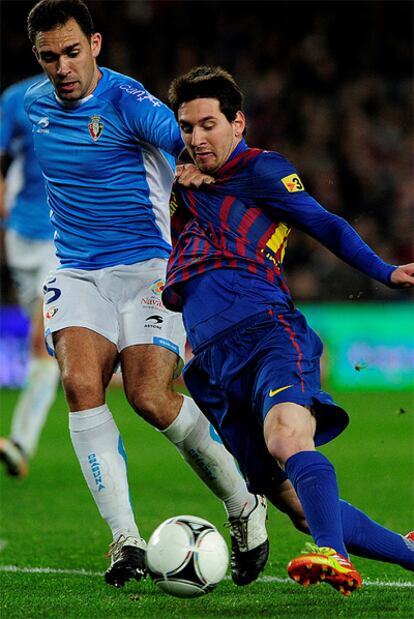 Messi trata de zafarse de un rival de Osasuna.