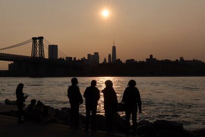 Un grupo de personas observa el atardecer desde Manhattan (Nueva York) donde se observa la bruma.
