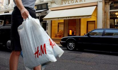 Una mujer con bolsas de H&amp;M pasea por la calle comercial Bond street (Londres).