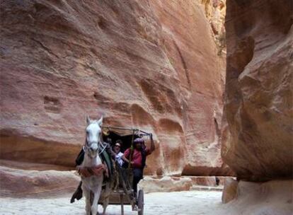 Una rudimentaria calesa, con turistas, atraviesa el desfiladero de arenisca que conduce a Petra, la ciudad rosa de los nabateos perdida en el desierto de Jordania.